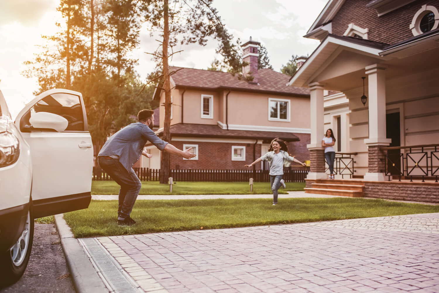 Dad arriving home and child running out on front lawn to greet him